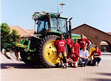 Stanford engineering graduate students standing in front of a GPS-guided tractor
