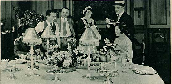 Norma Talmadge and others seated or standing near a dining table